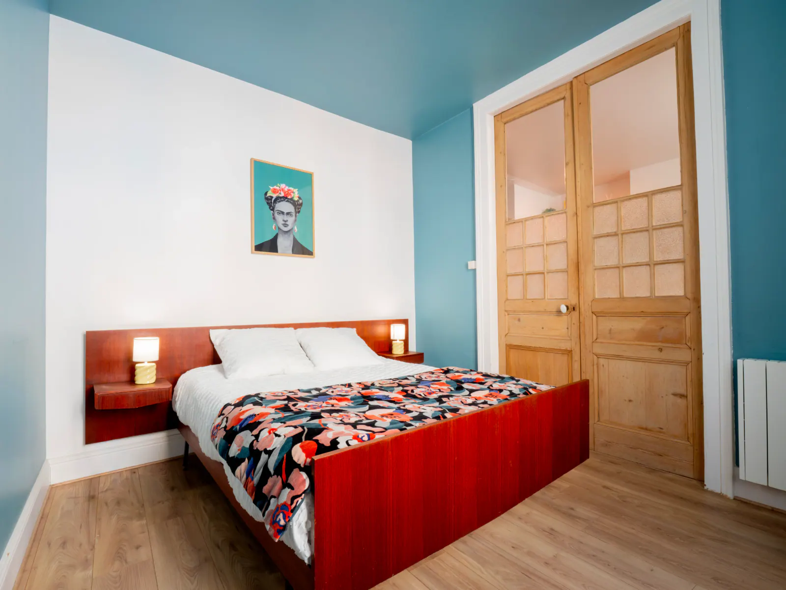 Chambre contemporaine aux murs turquoise et blanc, lit rouge avec chevet intégré, portes en bois clair