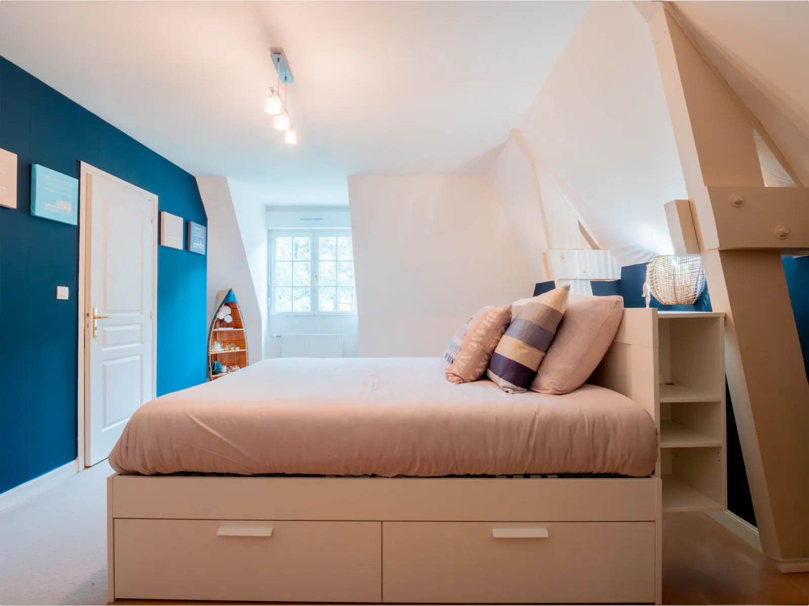 Chambre d'enfant avec lit mezzanine bois, murs bleu pétrole et blanc, fenêtre lumineuse