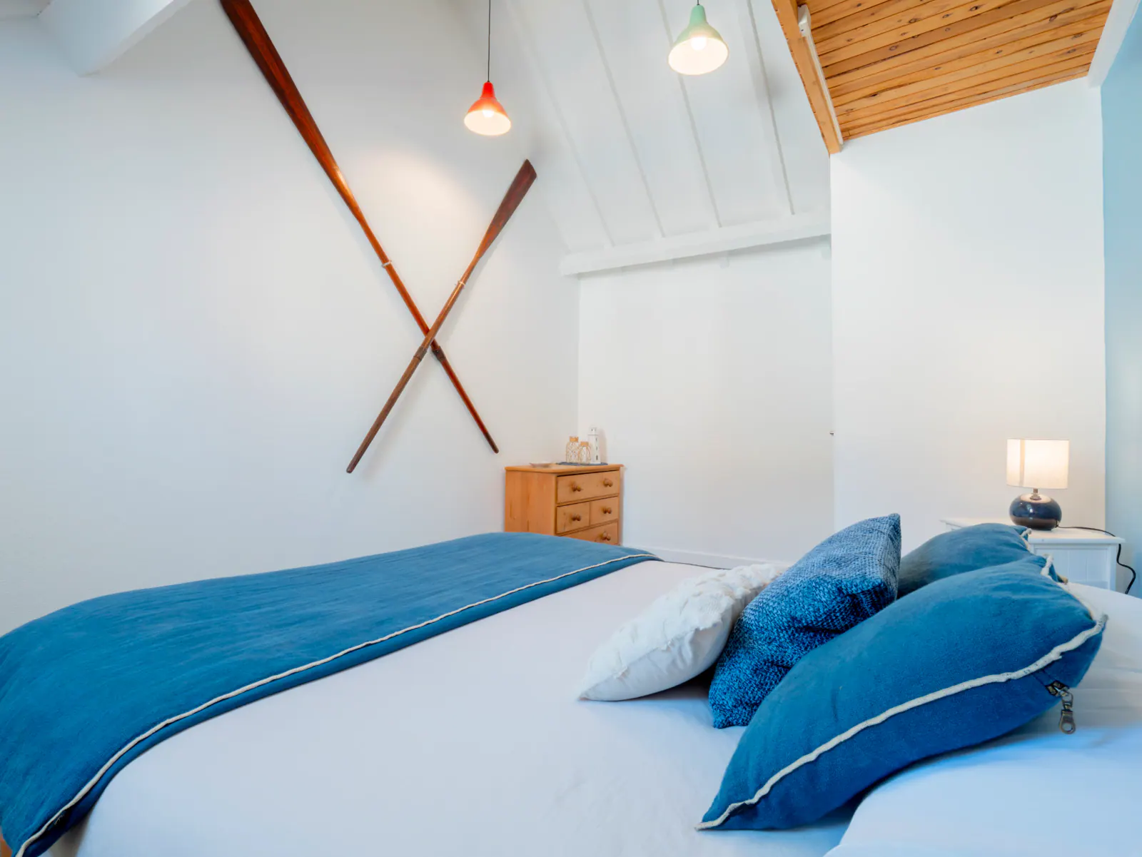 Chambre contemporaine avec lit double, parure bleue, mobilier bois et pendentifs design