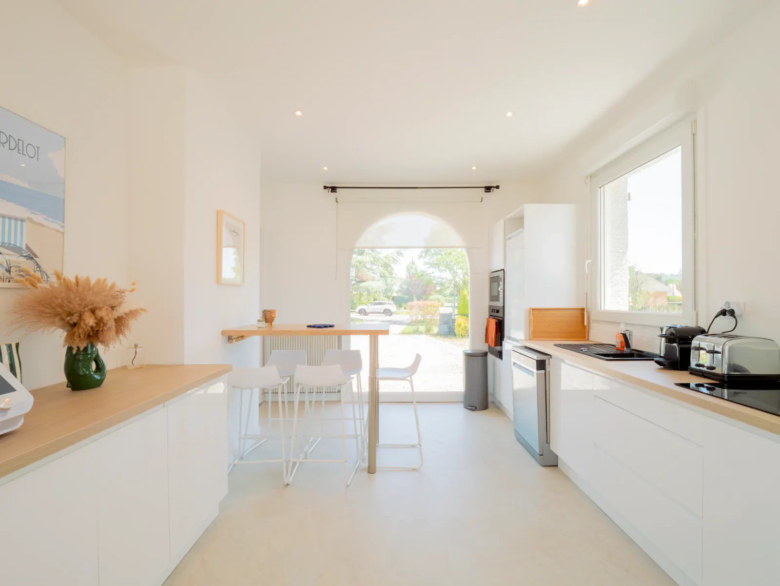 Cuisine ouverte contemporaine blanc et bois avec îlot central, baies vitrées et vue jardin