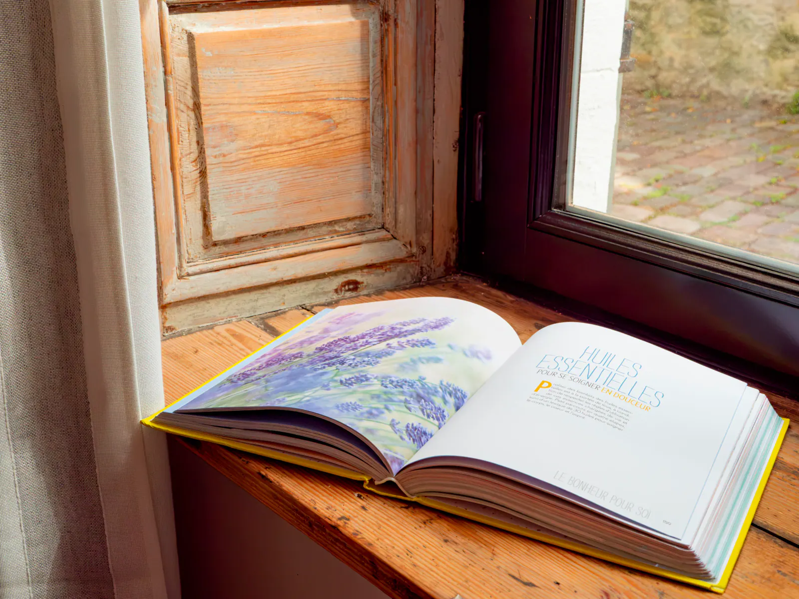 Livre ouvert avec illustrations de lavande sur le rebord d'une fenêtre ancienne en bois