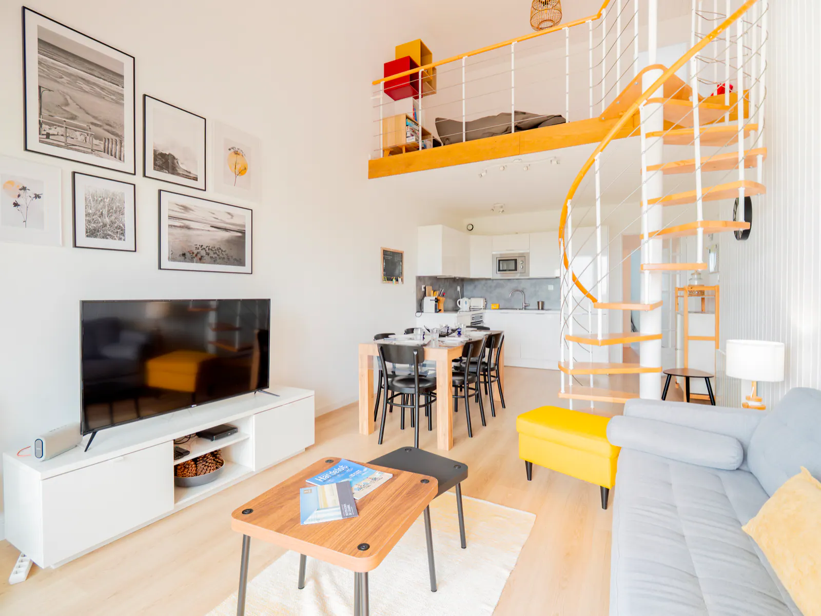 Salon lumineux avec escalier spiral jaune et blanc, cuisine ouverte, mobilier contemporain